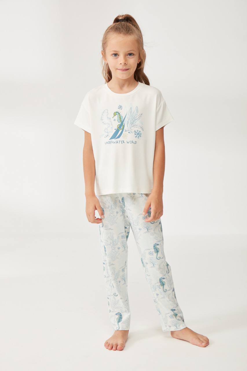 Girl wearing a white t-shirt with a whimsical underwater scene and matching aquatic print pants from Popjammies.