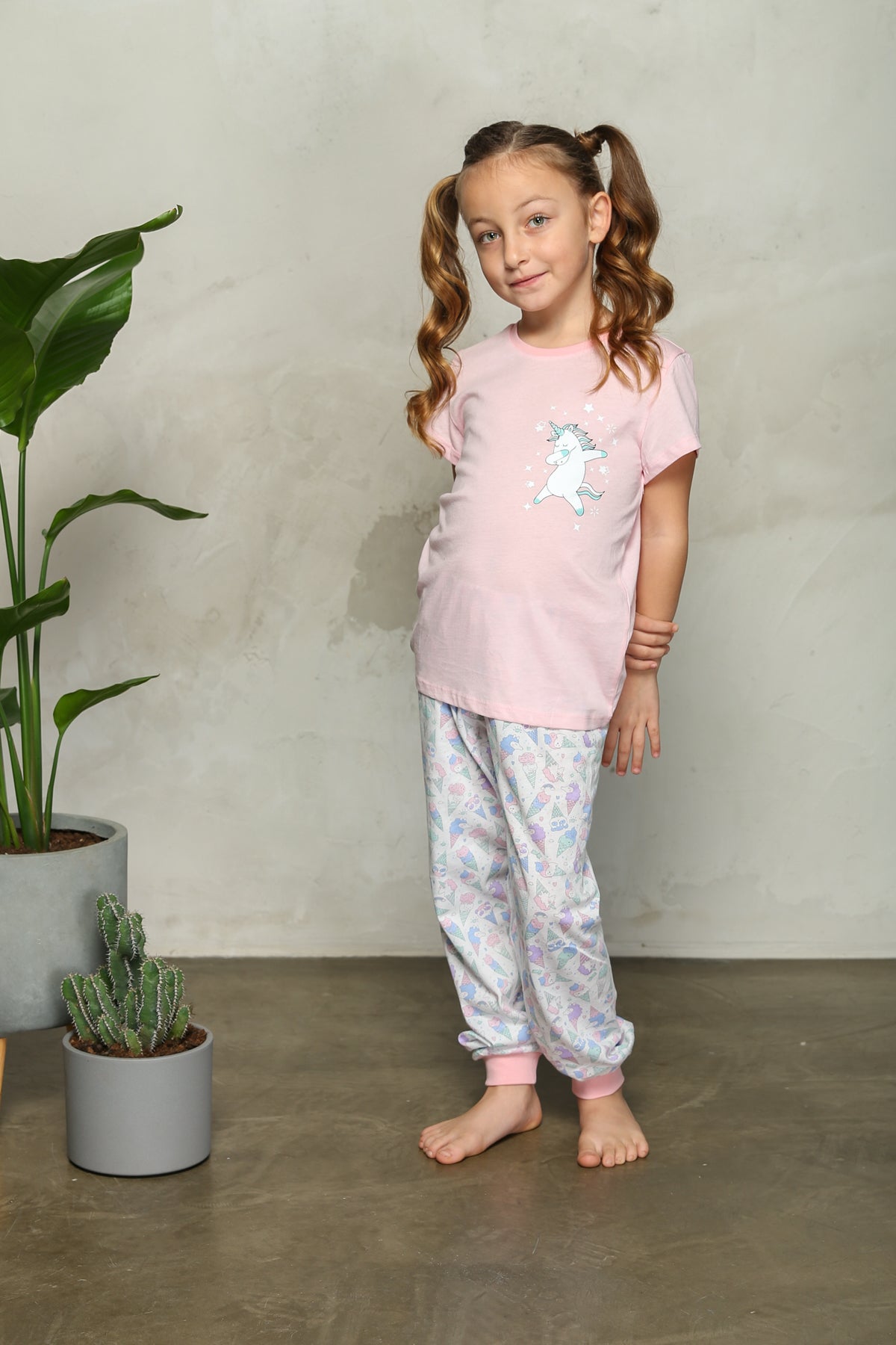 Girl in pink unicorn pyjama set standing with a smile