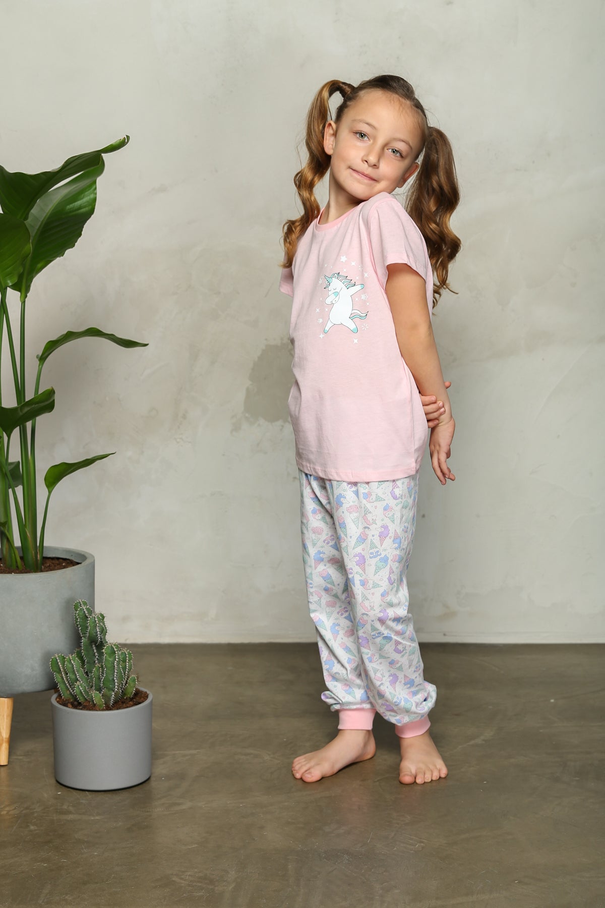 Girl wearing unicorn pyjama set standing with hands behind back