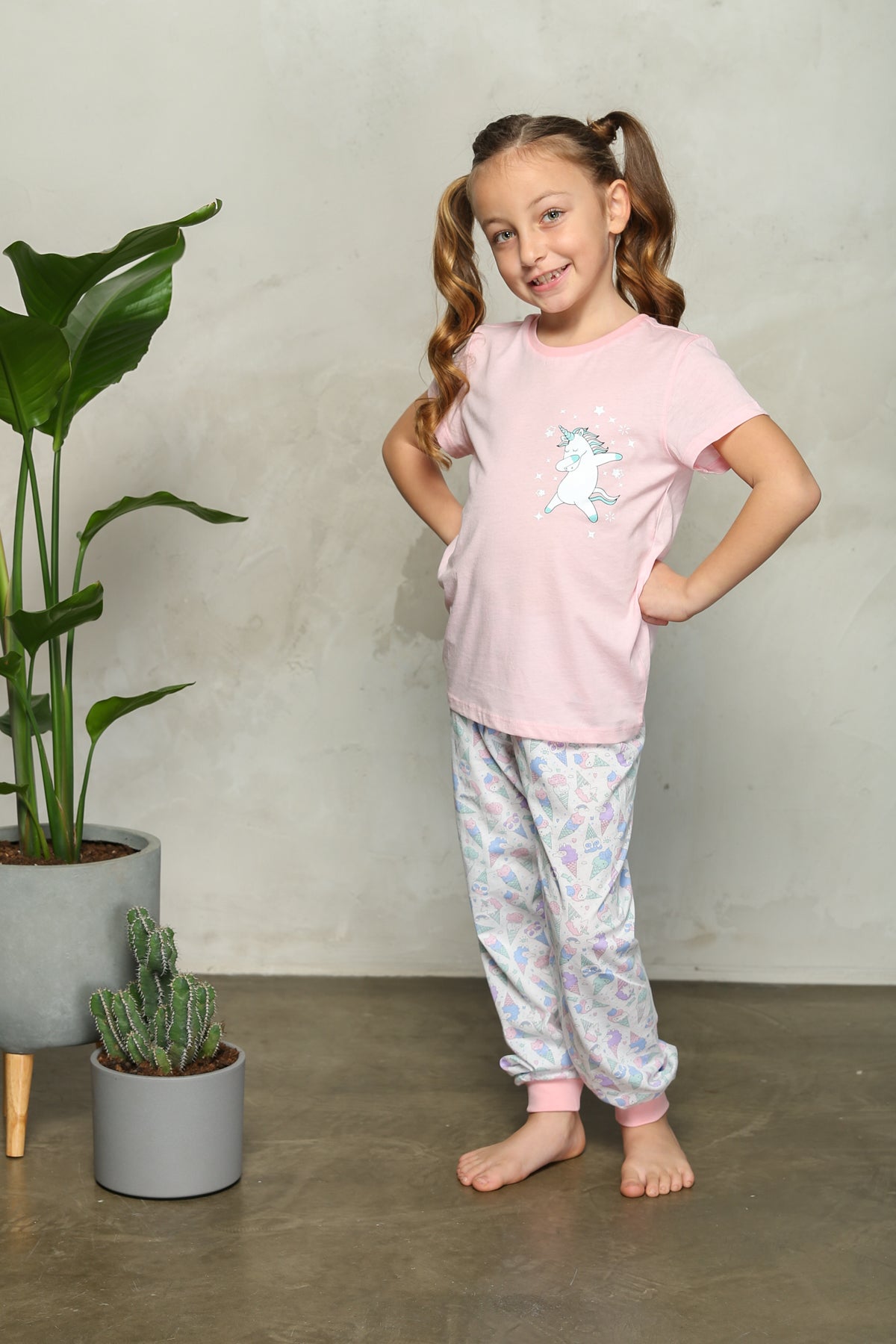 Girl posing in pink unicorn pyjama set with hands on hips